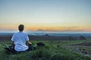 Person sitting on grass watching sunset