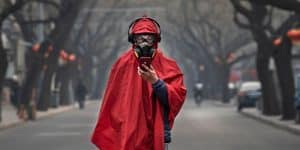 Person in middle of road with gas mask, headphones and looking at phone