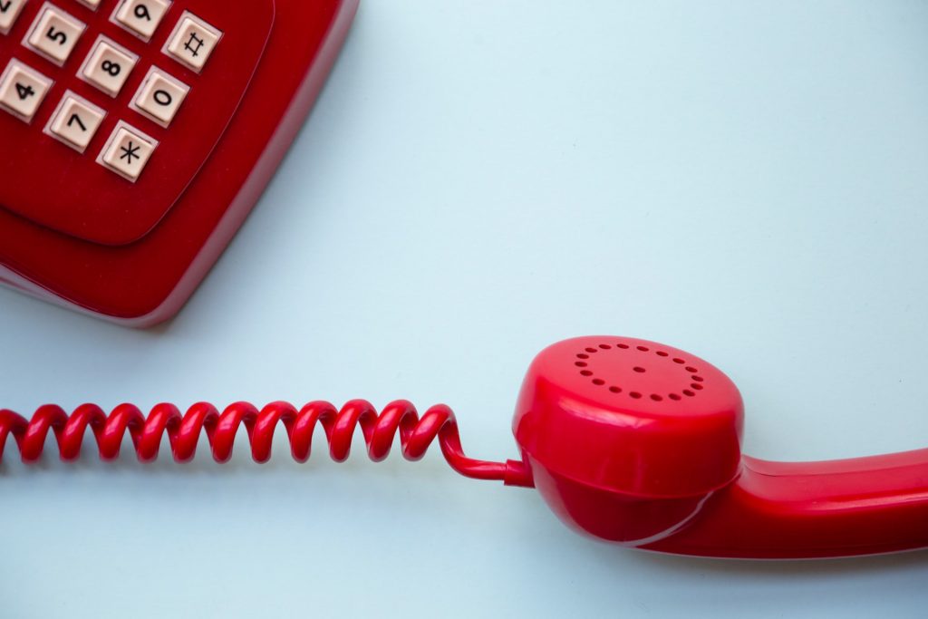 Old school telephone, red with receiver off the phone