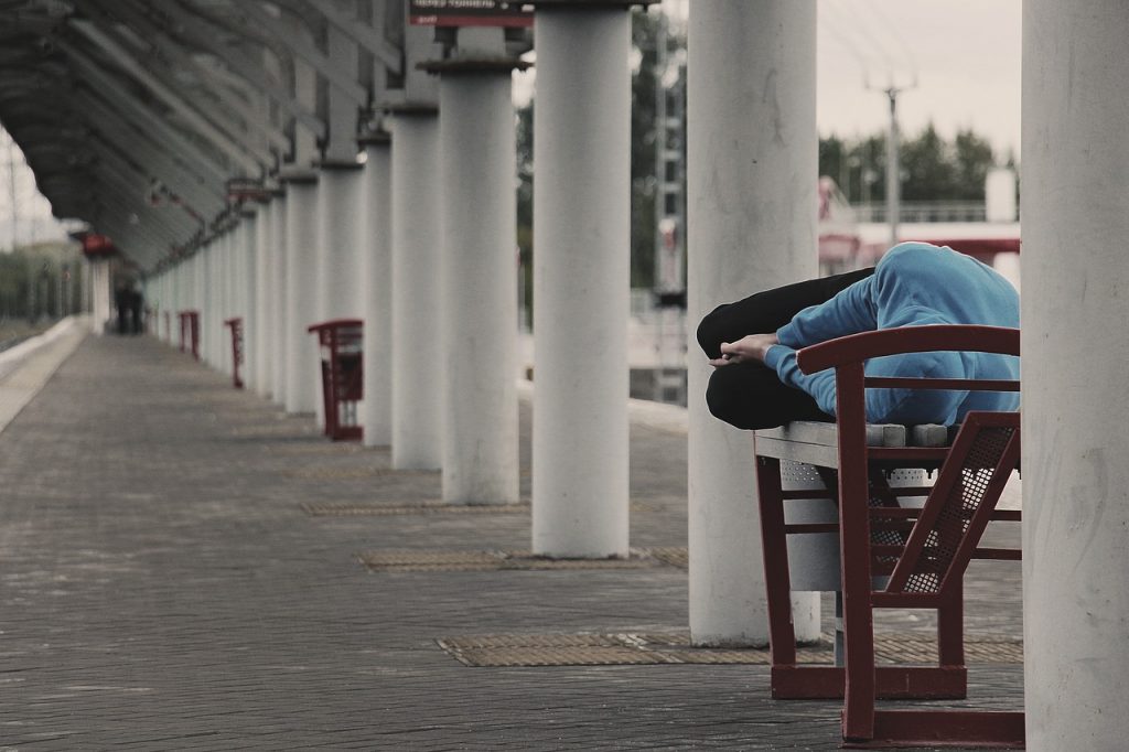 Person asleep on a train station bench