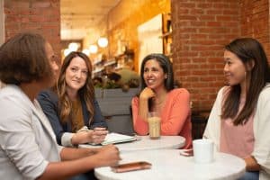 Four women sitting at a table and chatting.