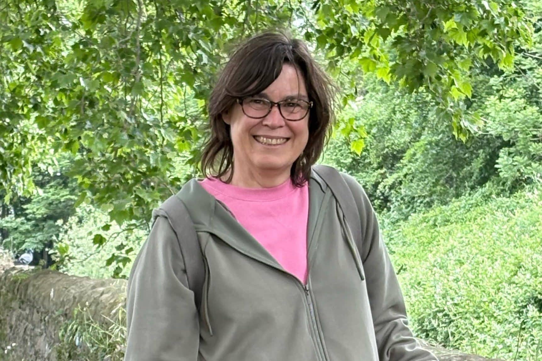 Portrait of Rebecca smiling in front of greenery