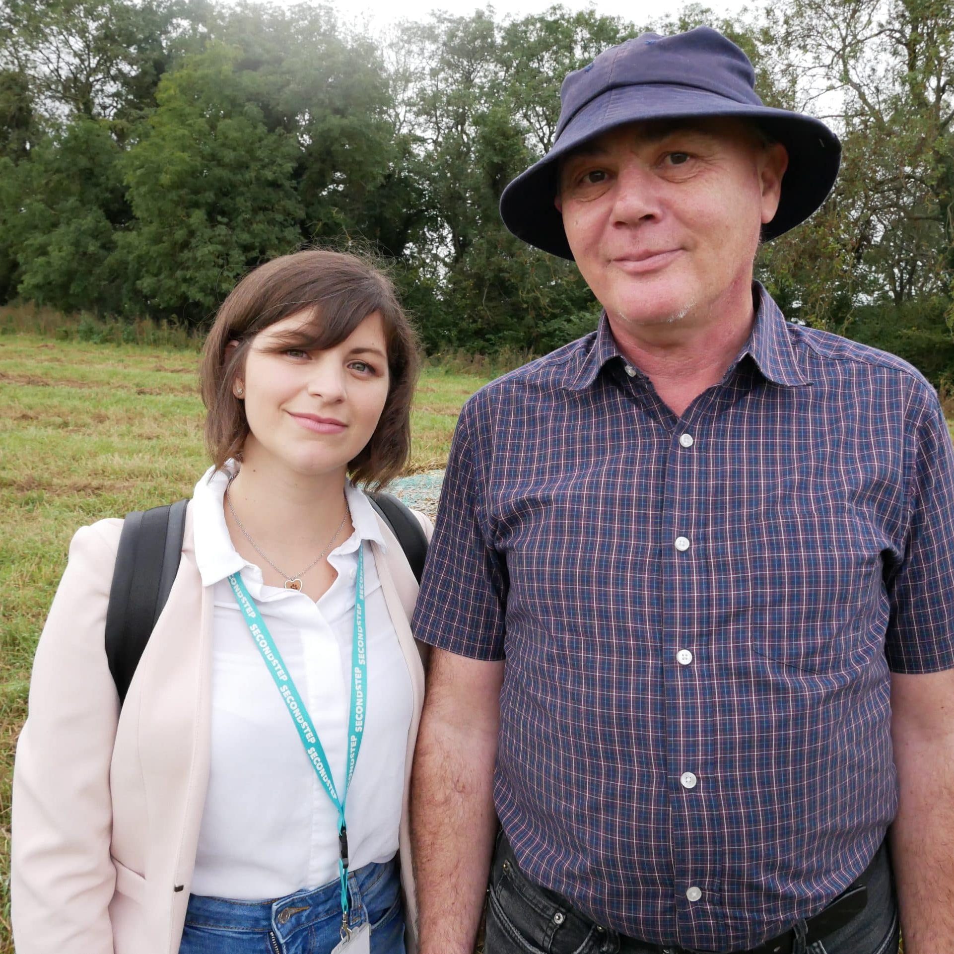 Cat and Tom standing in nature and smiling at the camera