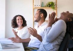 Cheerful employees talking and laughing at workplace. Group of smiling workers having fun in office. Teamwork and relaxation concept