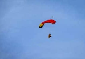 skydiver with parachute open against a blue sky