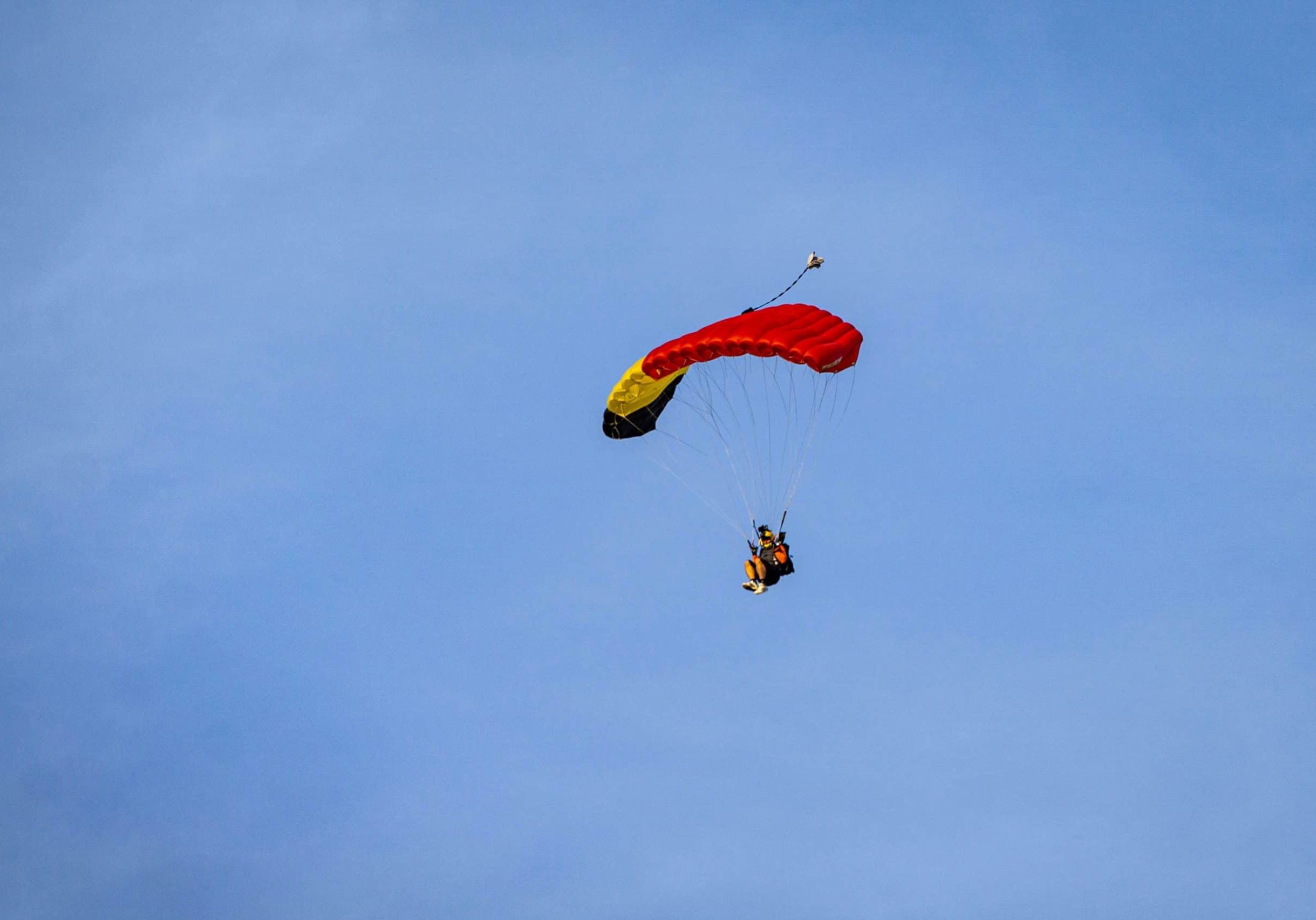 skydiver with parachute open against a blue sky