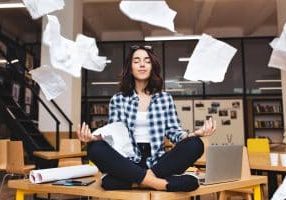 woman meditating on a table looking serene while papers fly around her.